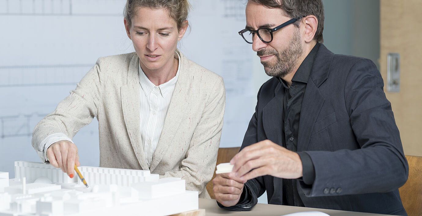 Claudia Meier und Markus Bachmann besprechen gemeinsam ein neues Architektur-Projekt als 3D-Miniatur